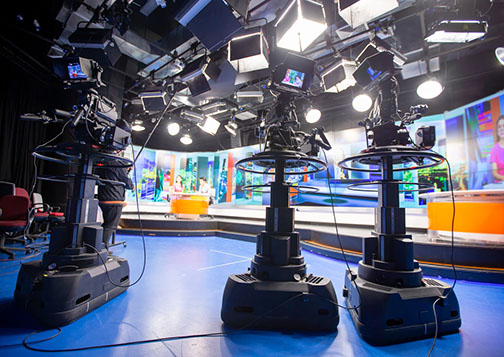 Behind the scenes of a news broadcast set featuring three cameras.