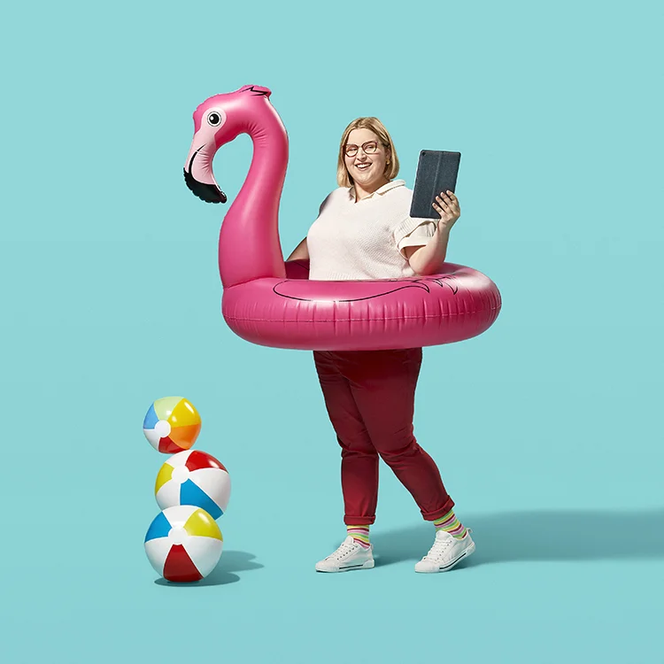 A Career Ready Student working on an iPad while inside of an inflatable flamingo inner tube,