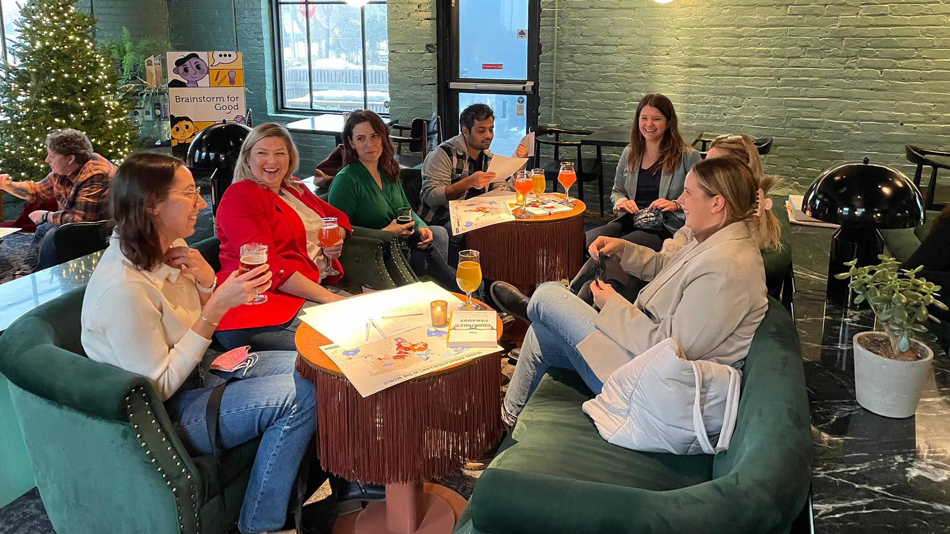 Group of people sitting around tables with drinks, brainstorming