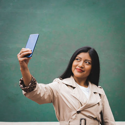 Person taking a selfie in front of a blackboard.