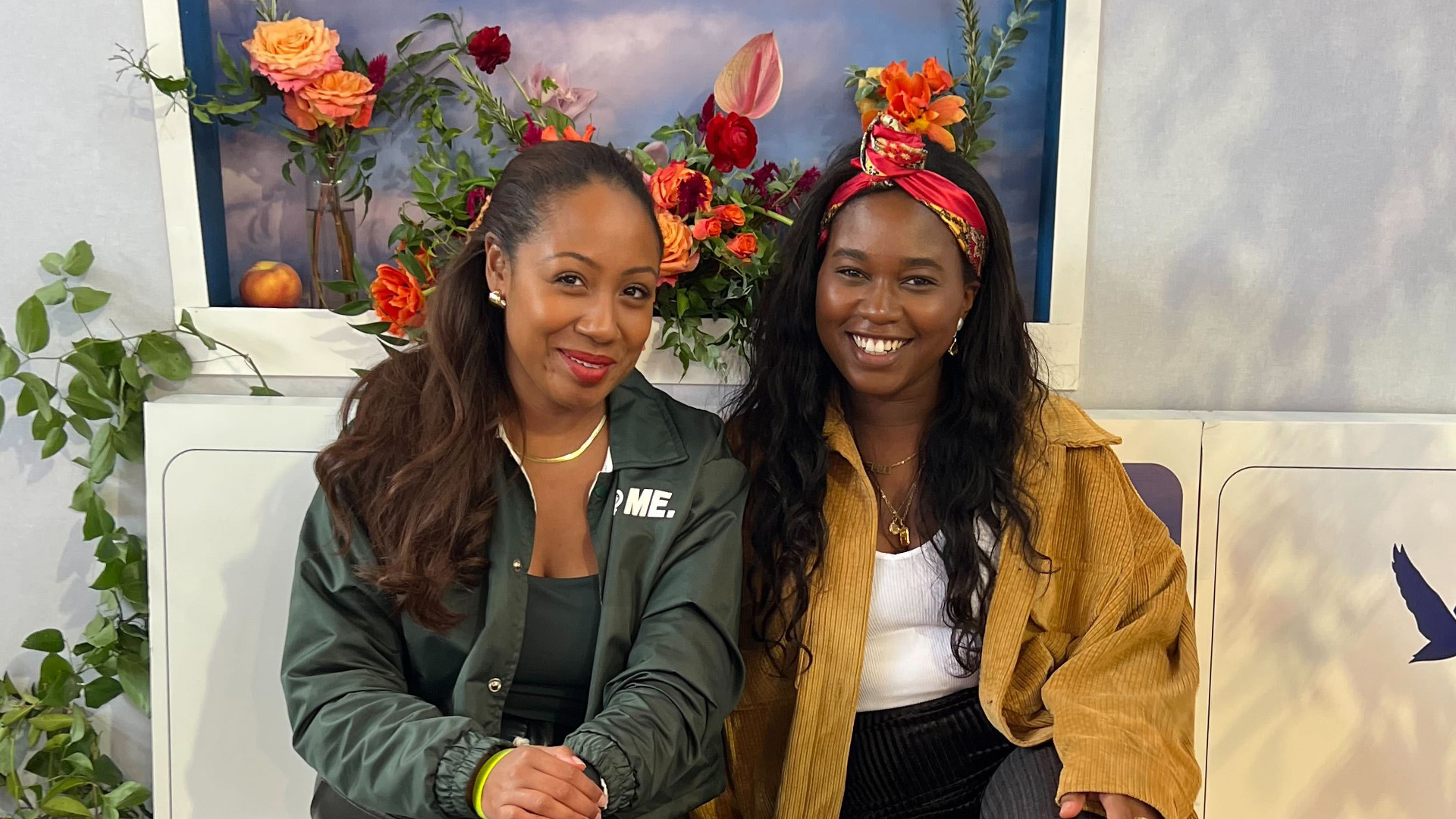 UpHouse team members Erica and Sade smiling in front of some flowers at CultureCon 2022
