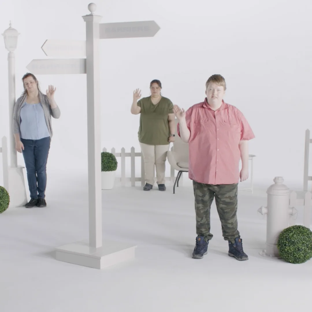 Three people with disabilities waving unenthusiastically from inside Barrier Town.