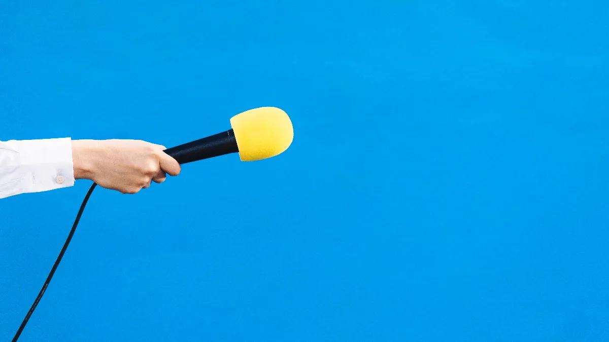 hands of a woman holding a yellow microphone