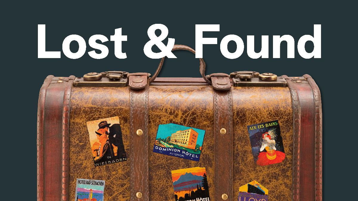 Decorative leather travel suitcase with destination sitckers and "Lost & Found" written above it.