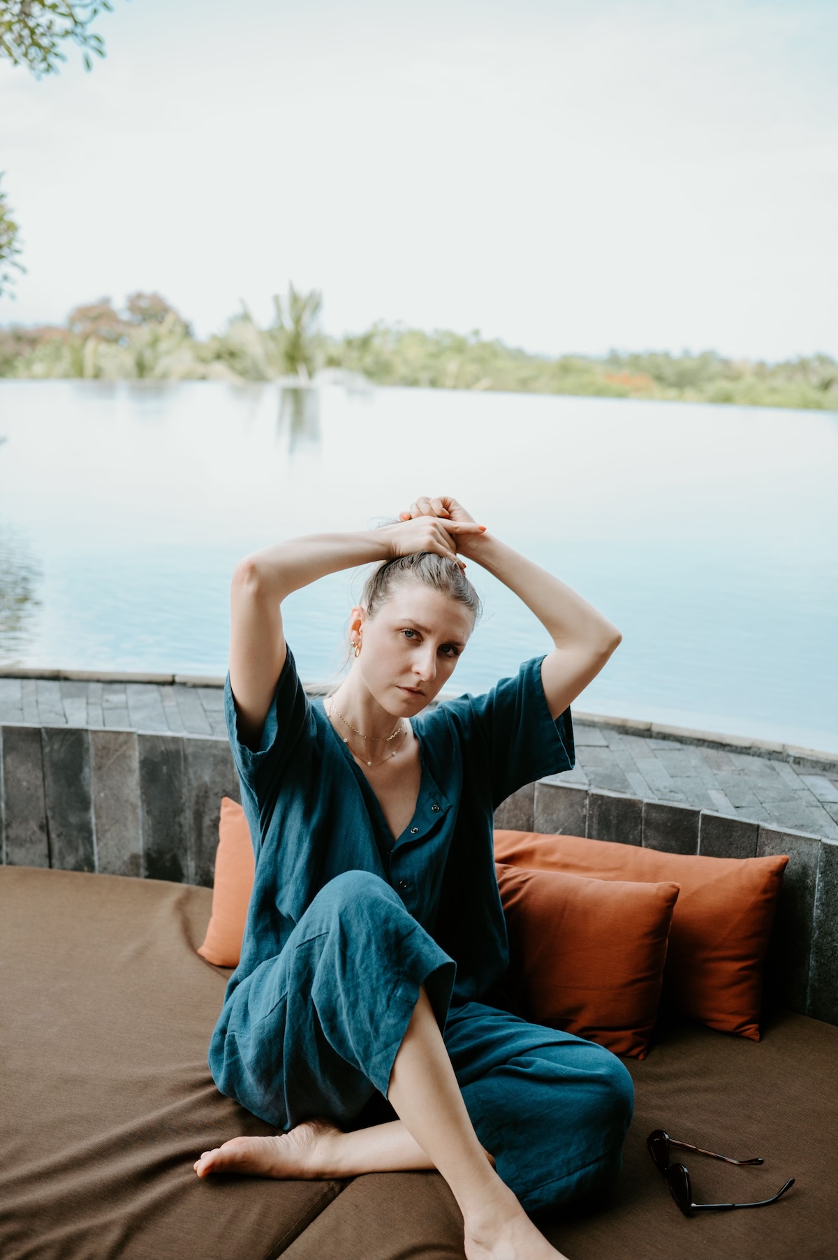 Kendra sitting near a lake, putting her hair up.