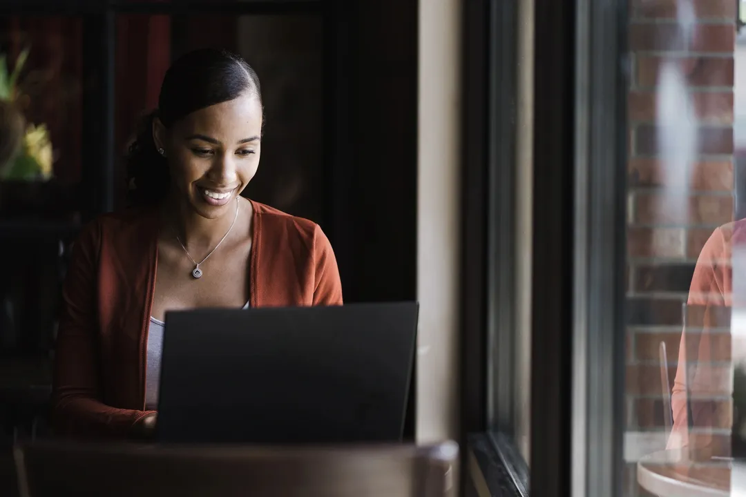 A person at their laptop nex to their window.