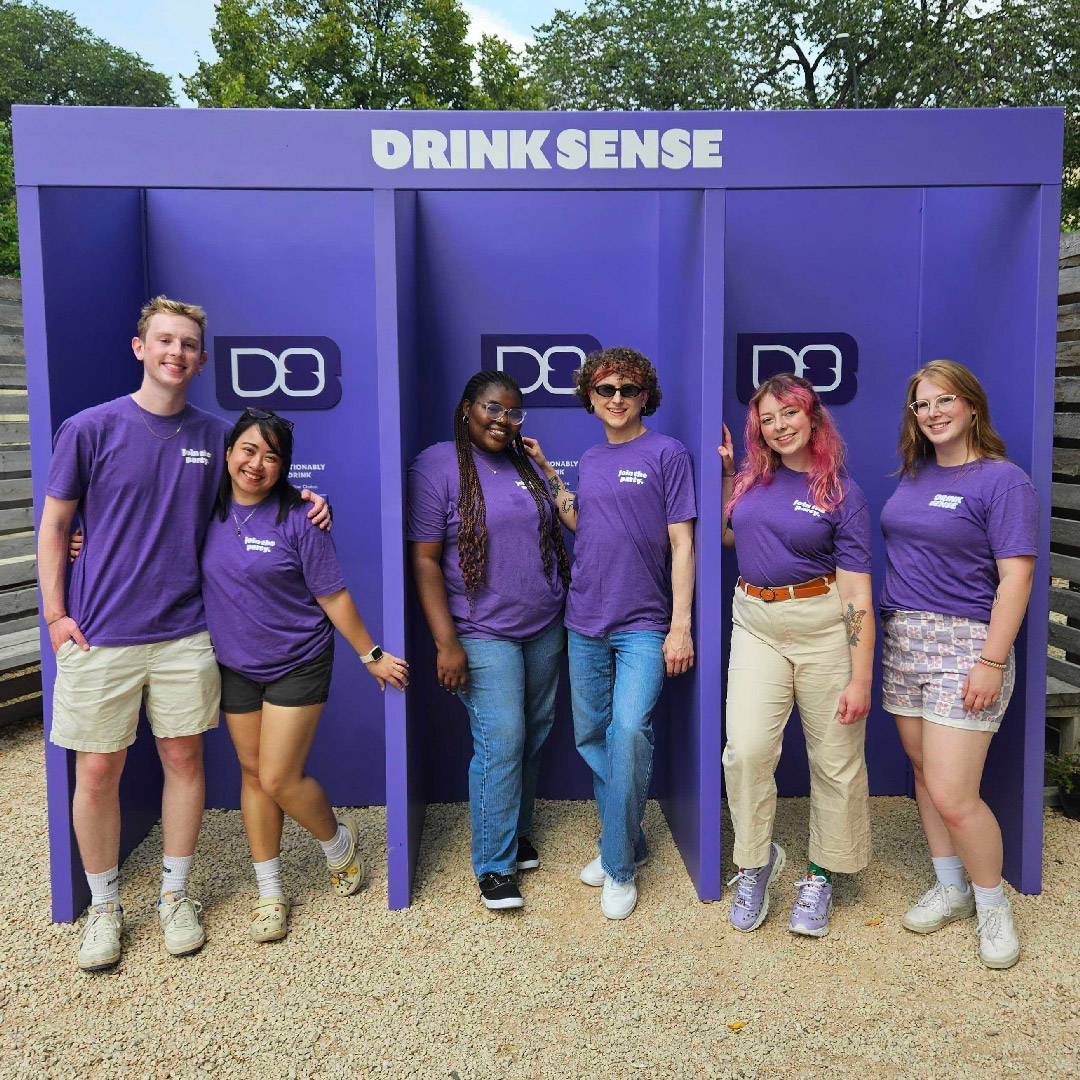 Scott and other brand ambassadors wearing DrinkSense shirts and standing in front of an outdoor DrinkSense booth.