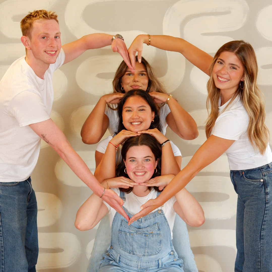 Scott and Sydney using their arms to each form half of a heart that frames Winnie, Julina and Ashna.