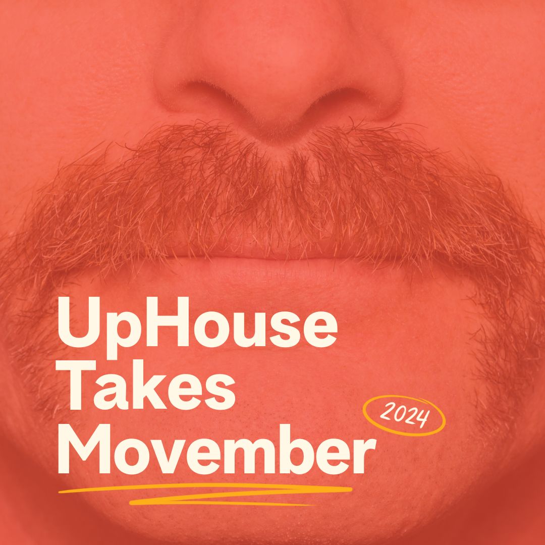 Close-up image of a mustache with the text 'UpHouse Takes Movember 2024' overlayed in bold off-white letters on a reddish-orange background, promoting UpHouse's participation in Movember, a campaign focused on men's health awareness.