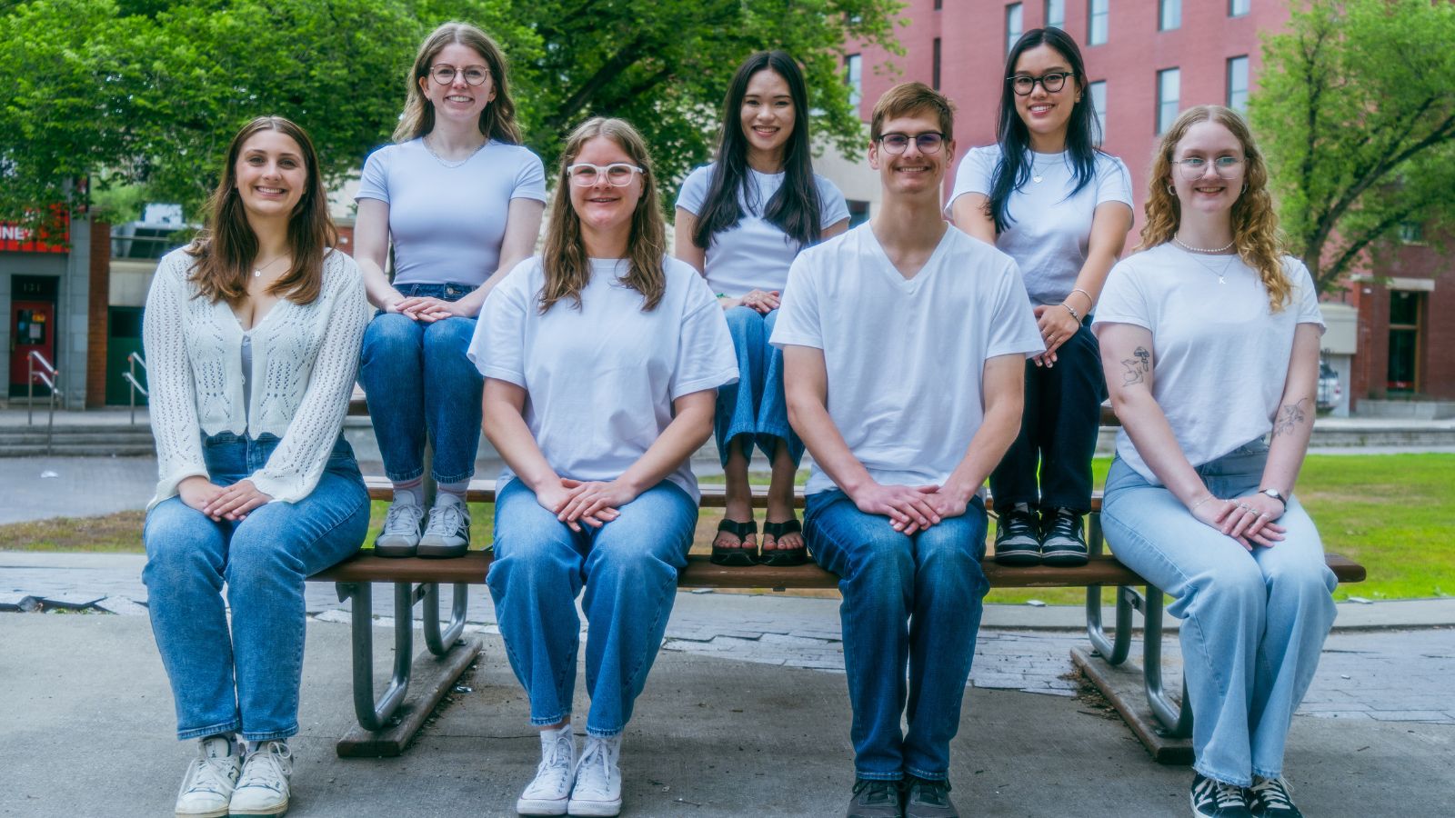 2 Seven people sitting on a picnic table smiling.