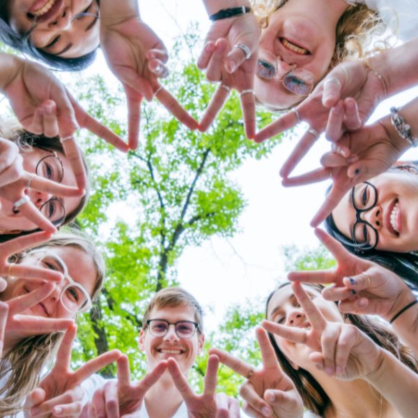 3 Seven people looking down at the camera while making a star with hands.