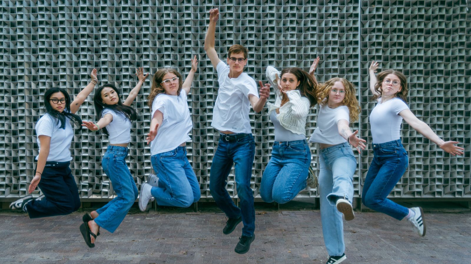 Summer Interns ’25 1 Seven people jumping and posing with serious expressions.