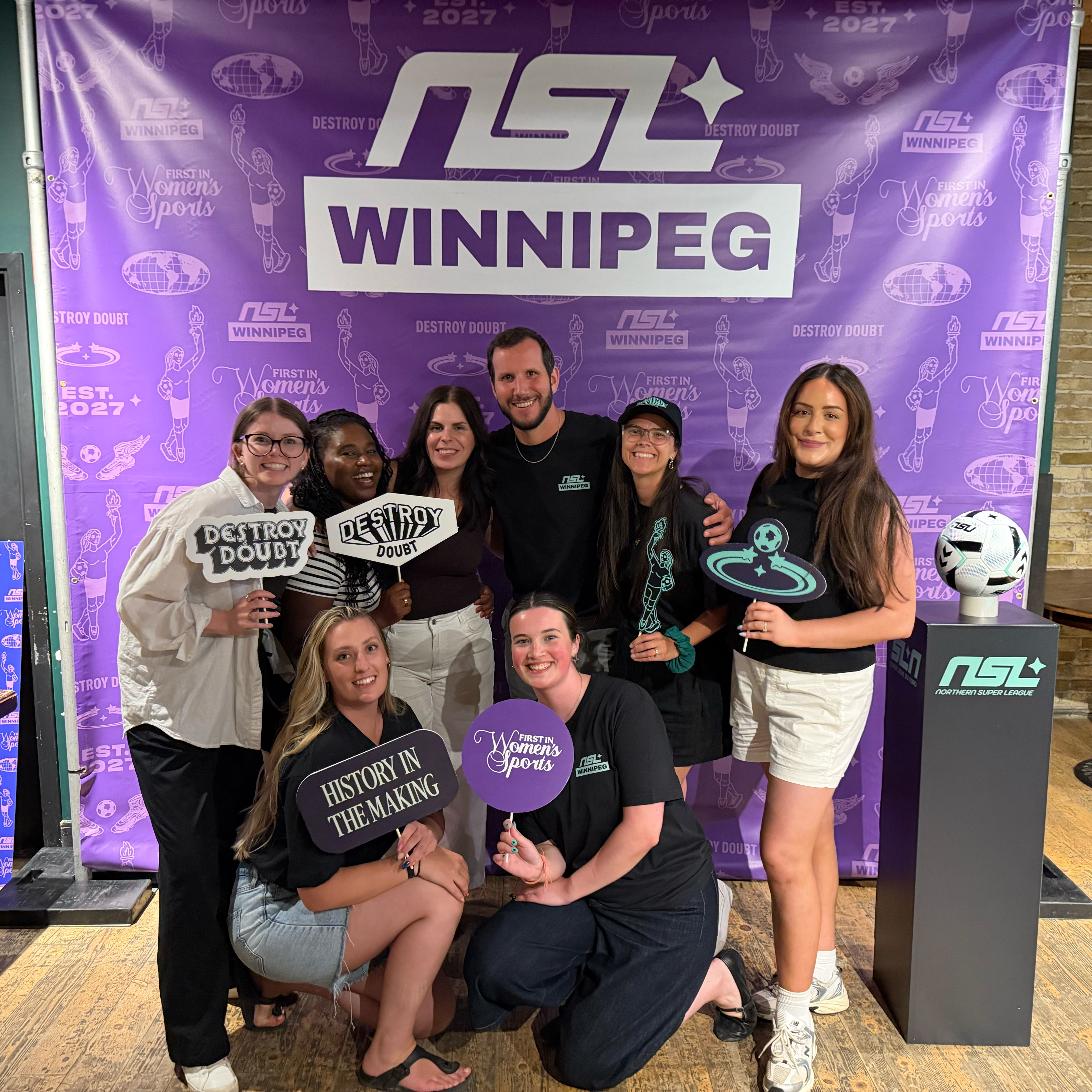 The UpHouse team in front of a NSL branded photo background.