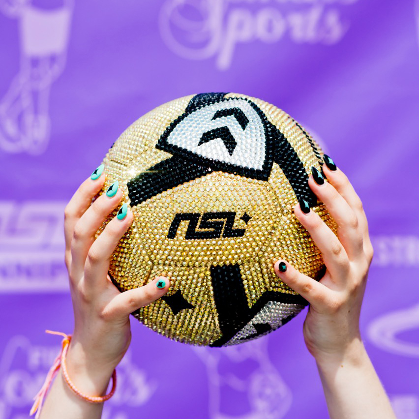 Hands holding a gemstone covered NSL soccer ball.